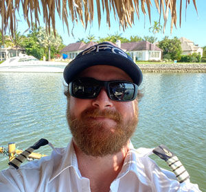 a man wearing sunglasses in front of a body of water